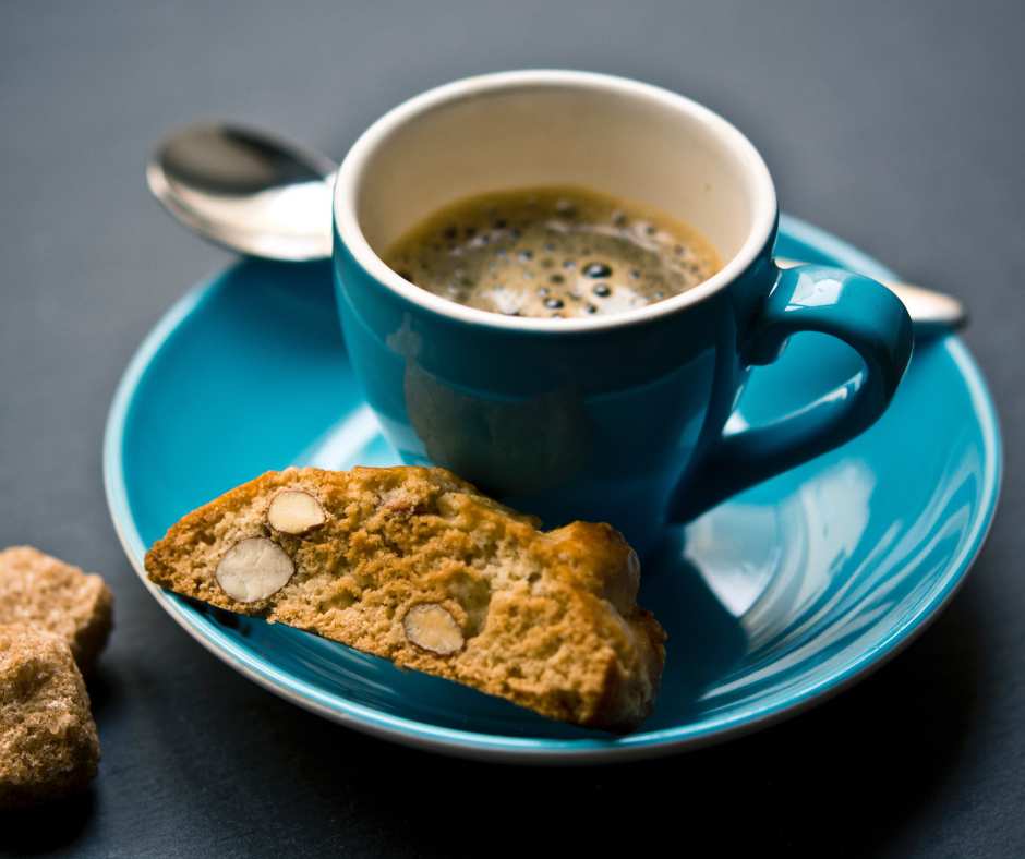 Espresso in turquoise cup with biscotti on marble counter