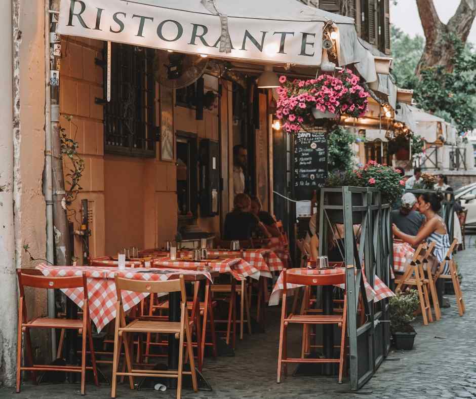 Outdoor Italian restaurant table with bread, water, and flowers.