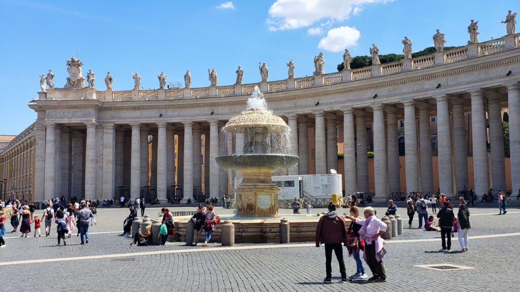 Fountains spraying water in St. Peter's Square with the colonnade in the background.
