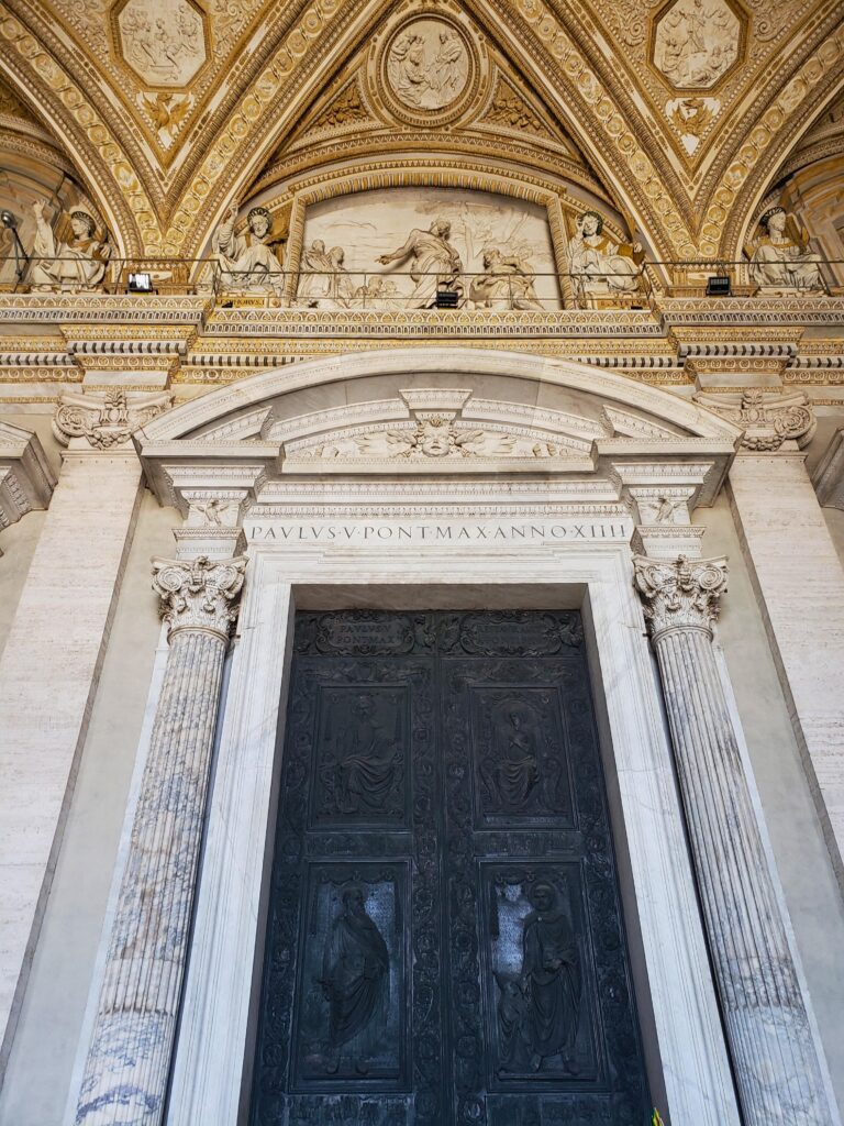 The massive bronze Holy Door at St. Peter's Basilica featuring detailed relief sculptures.