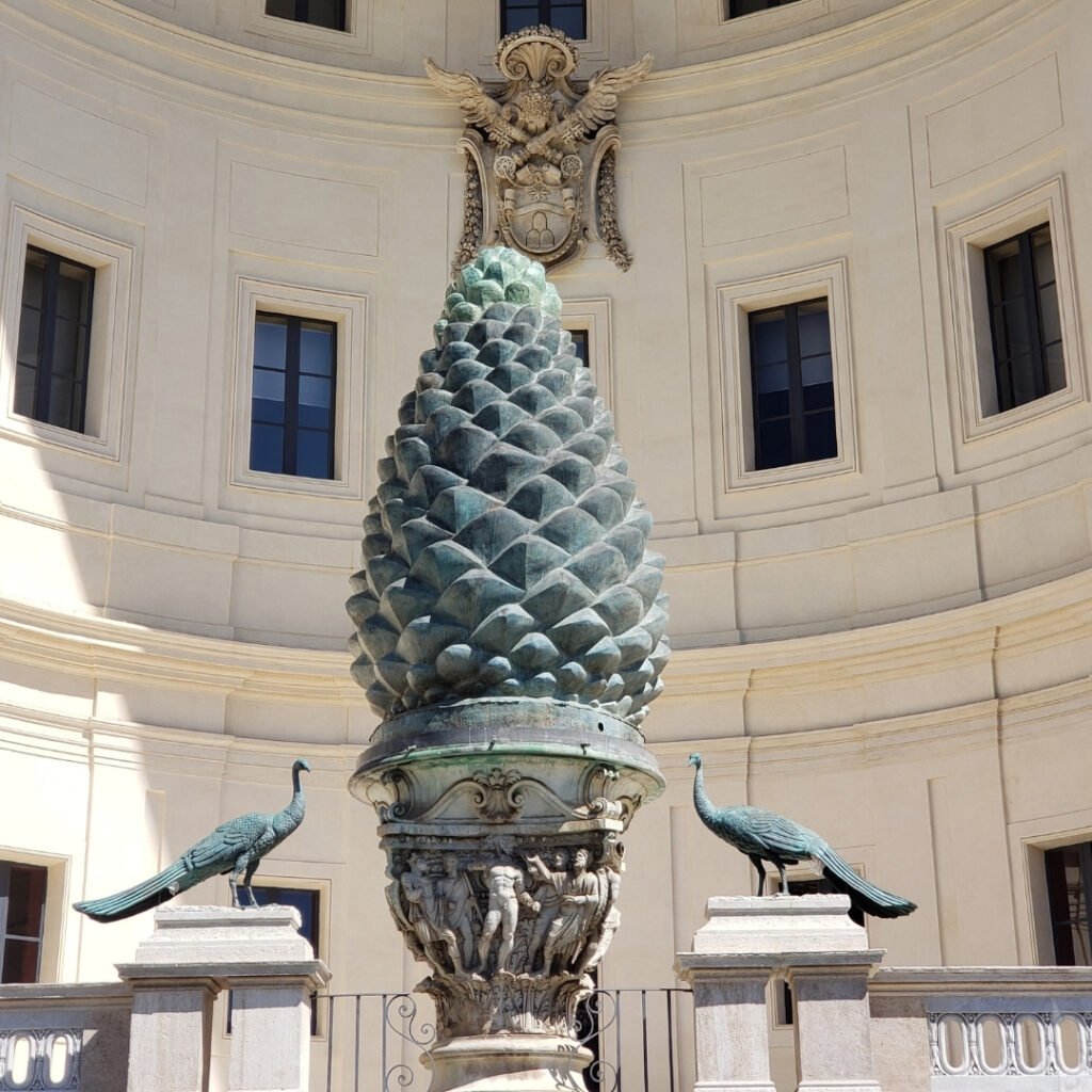 The massive ancient bronze pinecone statue and peacocks in the Vatican courtyard.