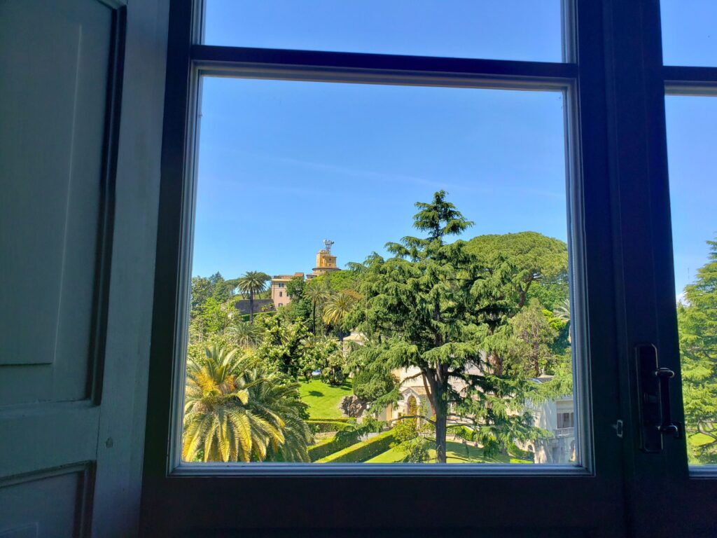 View through a window of the lush Vatican Gardens and the Vatican Radio tower