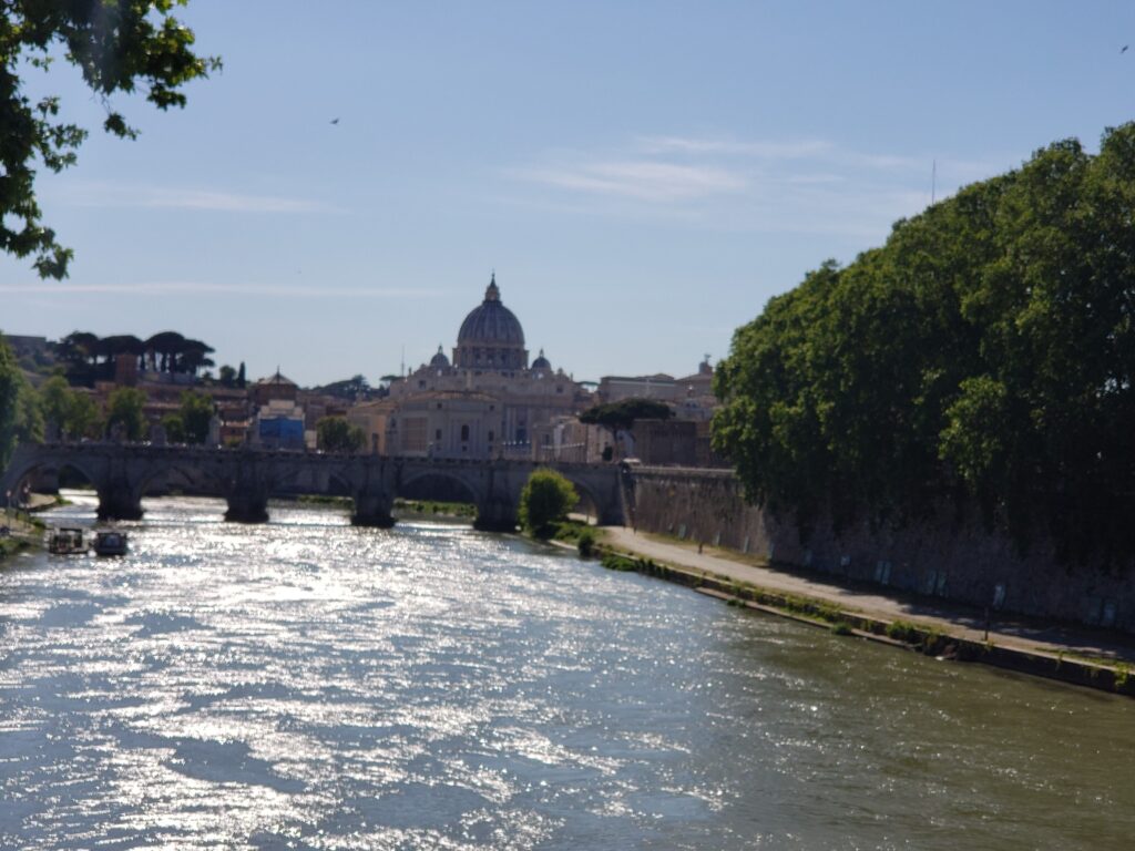 The sun sparkling on the Tiber River with St. Peter's Dome visible in the distance.