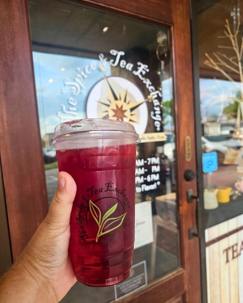 A tall iced hibiscus tea held outside The Spice & Tea Exchange storefront in Chattanooga.