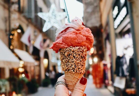 Hand holding gelato cone on an Italian street.