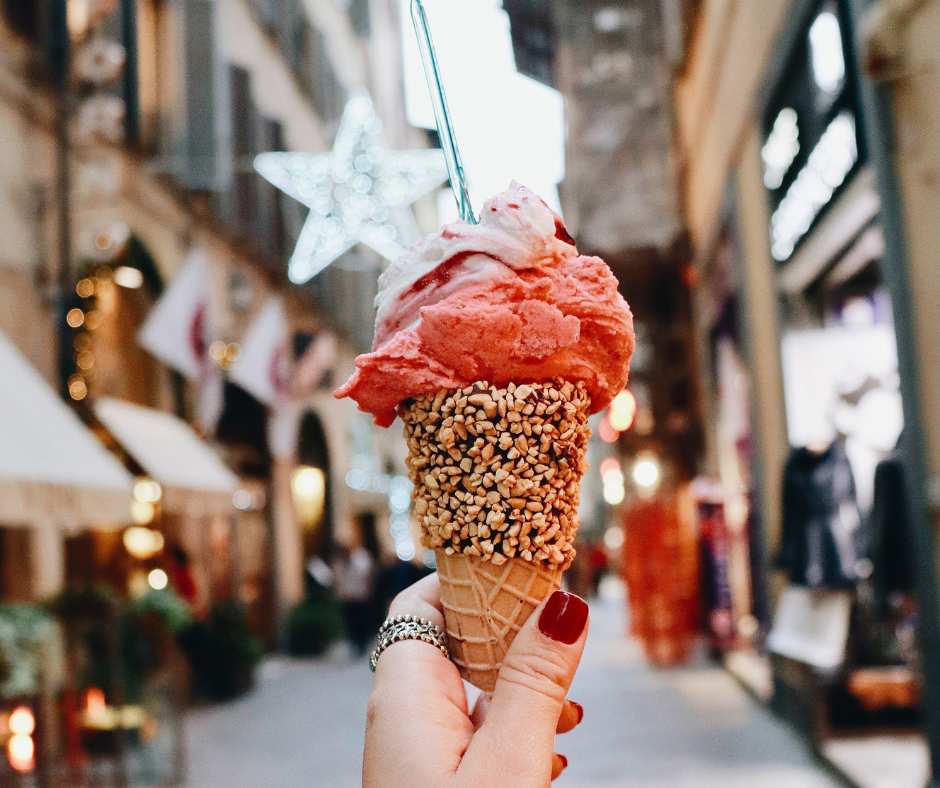 Hand holding gelato cone on an Italian street.