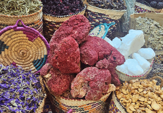 Colorful woven baskets filled with dried hibiscus petals, herbs, and spices in a traditional Egyptian market.